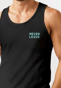 Muskulöser männlicher Oberkörper, der ein schwarzes Tanktop mit dem Text "NEVER LESS®" in Türkis auf der linken Seite trägt. Neutraler Hintergrund.