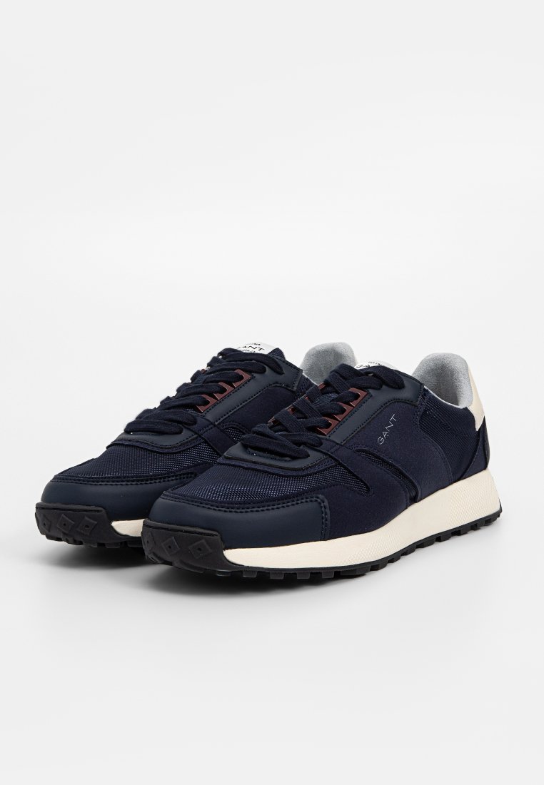 Marineblaue Sneakers aus einer Kombination von Textil- und Synthetikmaterialien, mit einer strukturierten Oberfläche, runder Zehenpartie, kontrastierender weißer Sohle und dunklen Schnürsenkeln.