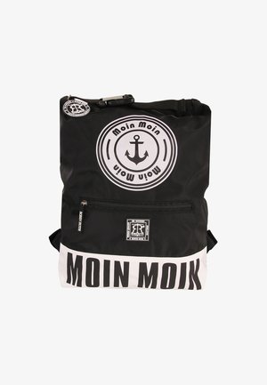 Sac à dos noir avec des accents blancs, comportant un logo d'ancre et le texte "Moin Moin". Fabriqué en matériau résistant à l'eau avec une poche à fermeture éclair.
