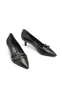 Zapatos de tacón bajo negros en punta con dobles tiras decorativas y hebillas plateadas sobre un fondo blanco.