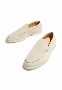 Beige suède instap schoenen met een ronde neus en een minimalist ontwerp, gekenmerkt door subtiele stiksels en een lichte zool.