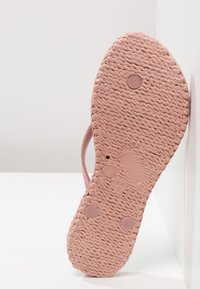 Rosa gummiflip-flop med texturerad sula som har cirkulära grepp och storleksdetaljen 'EUR 36' på undersidan. Minimalistisk design utan utsmyckningar.