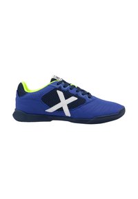 Zapatillas deportivas azules con un diseño de malla, parte superior sintética texturizada, logo blanco en contraste y acentos en verde brillante en el collar y los cordones.