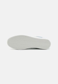 Fehér sneaker talp, textúrált halszálkás mintával. Simább felület, enyhe ív a saroknál, és nincs látható logó vagy minta.
