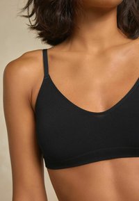 Sort bralette lavet af blødt stof, med tynde stropper og en glat finish. Designet har en rund halsudskæring og minimal syning.