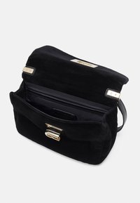 Schwarze Wildleder-Handtasche mit einem goldfarbenen Verschluss, einem offenen Innenraum und einem einzelnen Schultergurt. Strukturiert Oberfläche und elegantes Design.