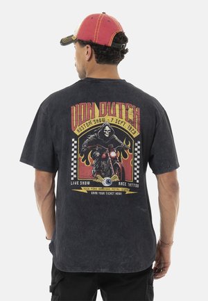 T-shirt en coton noir avec un graphisme vintage représentant un crâne et une moto. Le texte inclut "Von Dutch" et les détails de l'événement. Encolure ronde, manches courtes.
