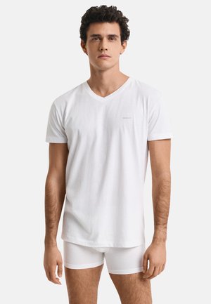 Witte katoenen v-hals t-shirt met korte mouwen, voorzien van een klein logo op de borst en een comfortabele, loszittende pasvorm. Gecombineerd met witte slipjes.
