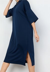 Navy blue dress with a collared neckline, loose short sleeves, side slits, and soft fabric, designed for comfort and ease of movement.