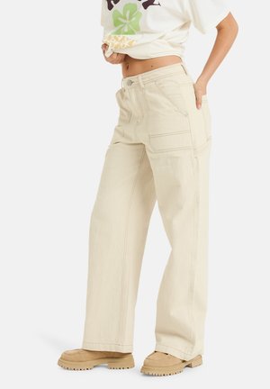 Beige weit geschnittene Hose aus strukturiertem Stoff mit Vorder- und Gesäßtaschen, kontrastierenden Nähten und hohem Taillenbund.