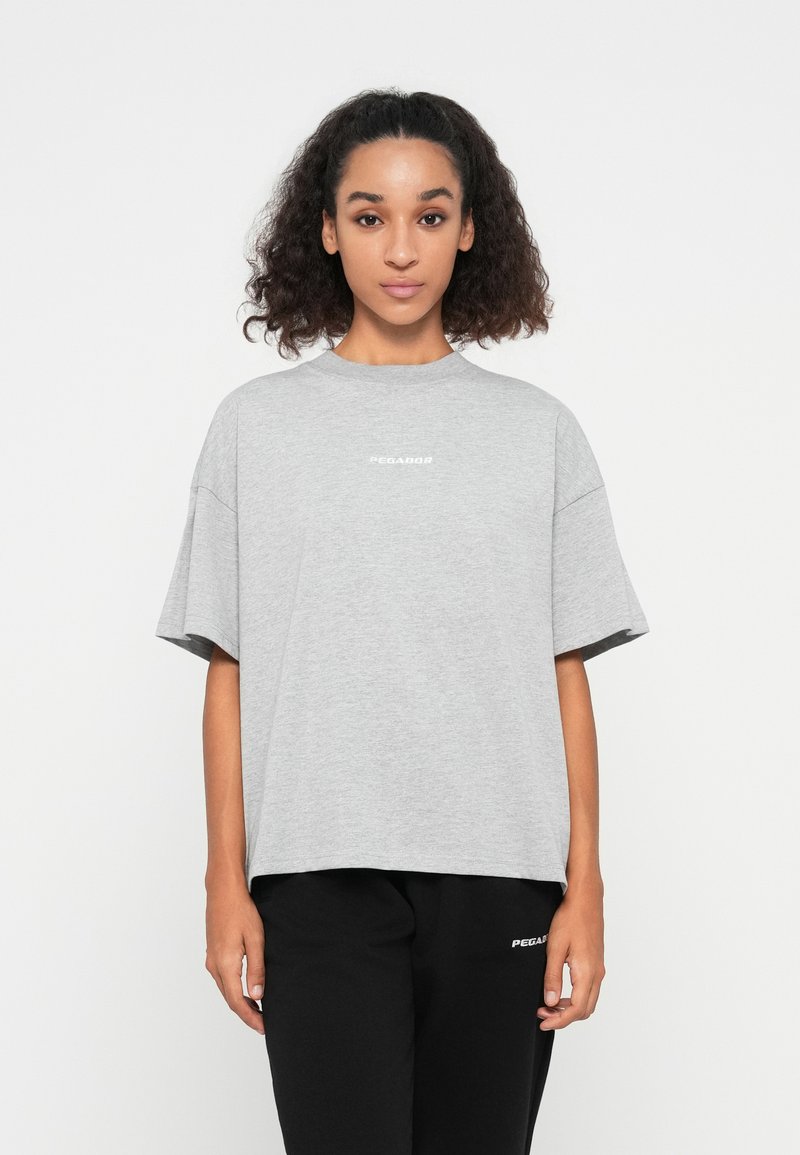Gray oversized t-shirt made of soft fabric, featuring short sleeves and a crew neckline, with "PEGADOR" printed in white on the front.