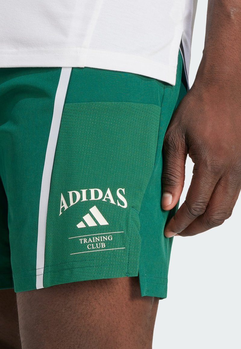 Pantalones cortos deportivos verdes con una tela texturizada, acentos laterales blancos y un logo de Adidas. Incluye un bolsillo y el detalle de texto "TRAINING CLUB".
