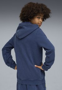 Felpa con cappuccio blu navy, dotata di tasca a marsupio, polsini e orlo a coste; presenta un cappuccio con cordini e una vestibilità comoda.