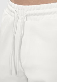 Vita sweatpants med en mjuk textur, med elastisk midja och dragsko. Inkluderar en sidficka med en minimalistisk design.