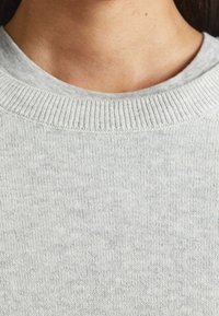 Pull gris avec un col côtelé et un tissu doux et texturé. Le matériau semble léger avec un motif chiné subtil.