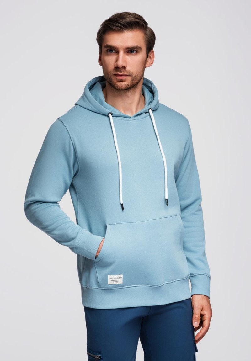 Felpa leggera blu chiaro realizzata in tessuto morbido, dotata di tasca frontale, cappuccio con stringa e stringhe bianche a contrasto.