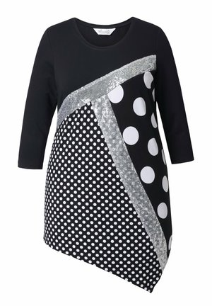 Musta tunika, jossa on isoja ja pieniä valkoisia pilkkuja, hopeisia yksityiskohtia sekä diagonaalinen kuvio, jossa on erilaisia kuvioita.