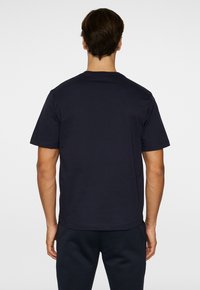 Mörkblå bomullströja med korta ärmar, rund halsringning och en avslappnad passform. Slät textur utan synliga mönster eller detaljer.