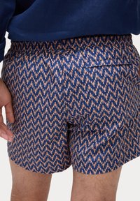 Granatowe szorty z wzorem homarów w kolorze koralowym. Posiadają elastyczny pas i tylnią kieszeń. Satynowa tekstura, gładkie wykończenie.