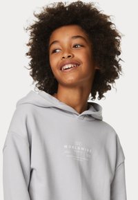 Lichtgrijze hoodie met een zachte textuur, voorzien van een grafische print in witte tekst op de voorkant. Inclusief een capuchon met trekkoord en een relaxte pasvorm.