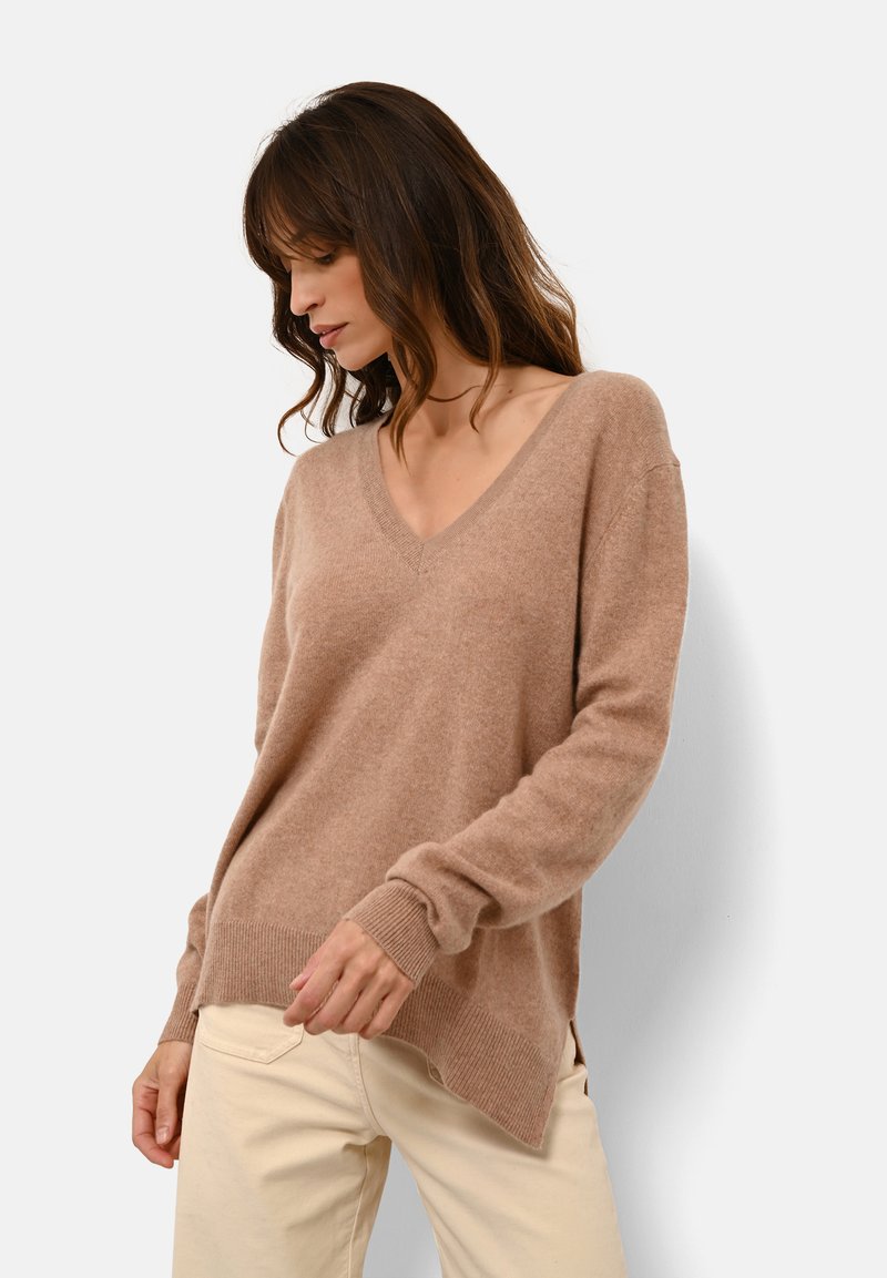Maglione a V, con maniche lunghe, realizzato in morbido materiale lavorato a maglia color marrone chiaro. Presenta polsini a coste e un orlo con spacchi laterali per una vestibilità comoda.