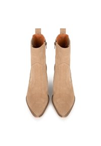 Botines de ante beige con punta afilada, cremalleras laterales y superficies texturizadas. Presentan un ribete cosido a lo largo de la suela.