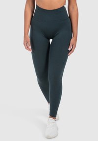Donkergroene high-waisted legging gemaakt van elastische stof, met een gladde textuur en een figuurvormend ontwerp.