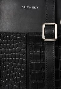 Zwarte leren tas met een gestructureerd, krokodillen effect design. Voorzien van een zilveren gesp en het ingegraveerde "BURKELY" logo op een gladde ondergrond.