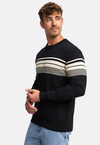 Schwarzer Pullover mit horizontalen weißen Streifen über der Brust. Er hat einen runden Ausschnitt, lange Ärmel sowie gerippte Bündchen und Saum.