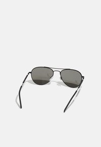 Sorte metal aviator solbriller med mørke linser og tynde rammer. Har justerbare næsepuder og fleksible ørestykker for komfort.