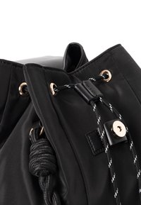 Schwarzer Nylon-Zugbeutel mit goldfarbenen Beschlägen und texturiertem Kordelverschluss. Verfügt über eine glatte Oberfläche und verstärkte Nähte.