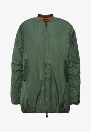 Vihreä pommitakki, jossa on vetoketju edessä, elastiset hihansuut ja sivutaskut. Valmistettu sileästä materiaalista, jossa on rypistyksiä hihoissa.