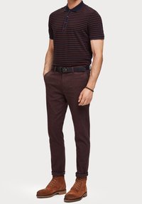 Koszulka polo w granatowo-bordowe paski, w zestawieniu z bordowymi spodniami o fakturze oraz brązowymi zamszowymi butami sznurowanymi. W zestawie czarny skórzany pasek.