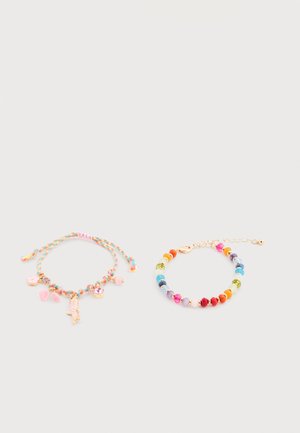 Deux bracelets colorés sur un fond clair : l'un tressé avec des breloques roses, l'autre en perles avec des pierres multicolores et des accents dorés.