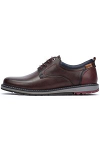 Zapatos marrones de cuero con cordones, con una textura suave, suela gris contrastante y detalles de costura; cuentan con una pestaña en el talón.