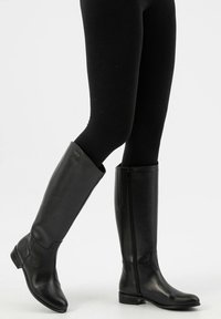 Stivali neri in pelle fino al ginocchio con una finitura liscia, cerniera laterale e tacco basso, dotati di punta rotonda e minime accentuazioni in metallo.
