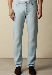 Světle modré džíny vyrobené z denimu. Mají rovný střih, pět kapes, kontrastní švy a zapínání na knoflík.