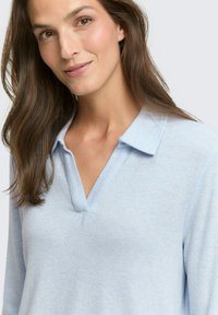Hellblauer Pullover mit V-Ausschnitt und strukturiertem Kragen. Weiche Textur und lange Ärmel. Schlichtes, sauberes Design ohne Muster oder Akzente.