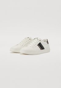 Hvite sneakers med en glatt lærfinish, med en svart side stripe og leopardmønsterdetaljer. Lissene er runde.