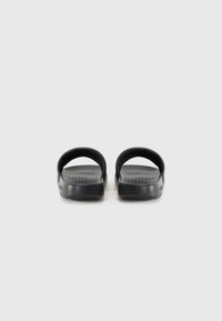 Black sandals with a textured footbed, open toe, and wide straps. Made of rubber, featuring a solid design and a low-profile sole.