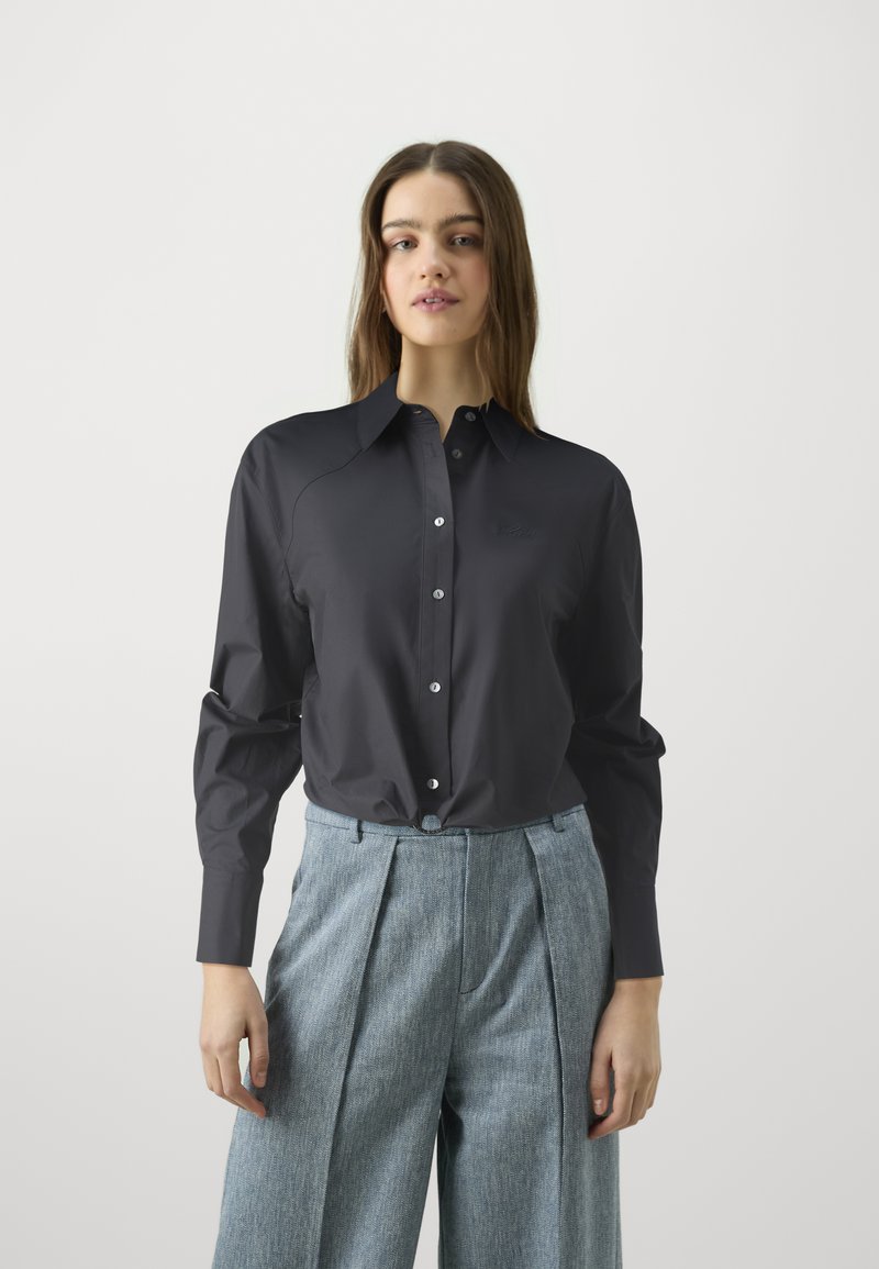 Σκούρο μπλε πουκάμισο με γιακά, μακριά μανίκια και κομψό σχεδιασμό. Διαθέτει έναν διακριτικό λογότυπο και λεπτομέρεια στη σφιχτή μέση.