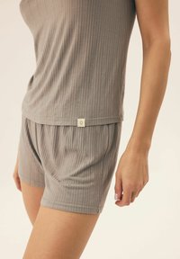 Gray ribbed loungewear set with a sleeveless top and matching shorts. Features a subtle logo tag on the waistband and soft texture.