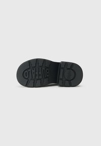 Crna gumena potplat čizme s istaknutim uzorcima i utisnutim logotipom "BUFFALO". Glatka površina s definiranim žljebovima za prianjanje.