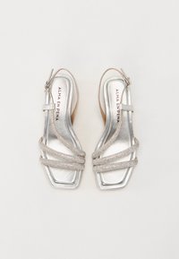 Hopeasäihkeät slingback-sandaalit, joissa on ristikkäiset kimalteiset remmit ja neliönmuotoinen kärki. Silkkinen materiaali, matala korko, brändätty pohjallinen. Klassinen muotoilu.
