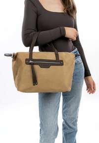 Tan suede handbag with dark brown leather accents, zippered pocket, and two sturdy handles. Soft texture and rectangular shape.