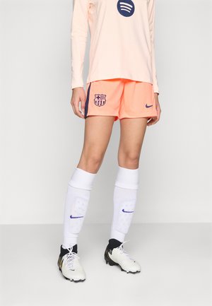 Nike Barcelonas fotbollströja har en ljusrosa långärmad tröja, orange shorts med en laglogo, vita strumpor och svartvita fotbollsskor.