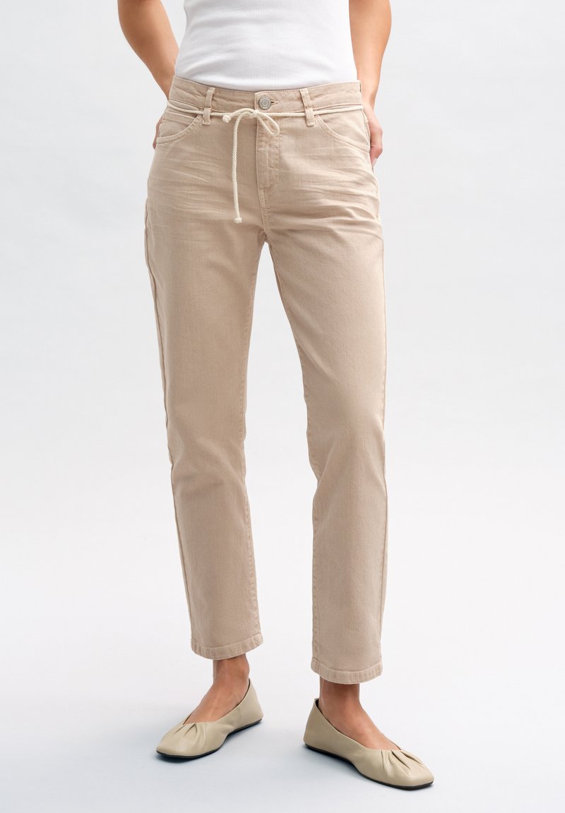 Pantaloni in cotone beige con vestibilità comoda, vita con cordoncino e tasche laterali. Tessuto morbido con design minimalista e orli arrotolati.