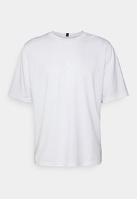 Vitt t-shirt med kort ärm tillverkat av smooth material, med en subtil, broderad svart Jumpman-logga på bröstet och rund halsringning.