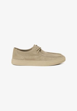 Beige suède casual schoen met veters aan de voorkant, gestikte details op de teen en een platte rubberen zool.