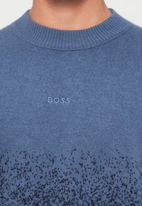 Suéter azul de malha com gola redonda canelada. Apresenta uma textura de gradiente subtil e o logótipo "BOSS" em azul mais claro no peito.